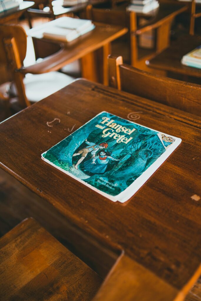 Illustrated fairy tale book 'Hansel and Gretel' on a wooden classroom desk, evoking childhood nostalgia.